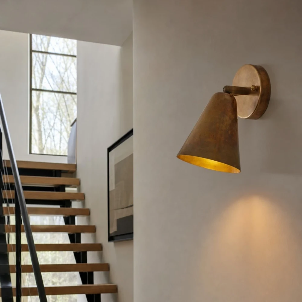 Brass cone wall lamp on stair landing wall