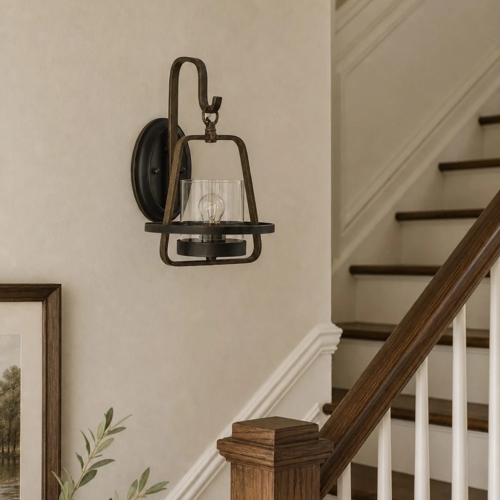 Clear glass wall sconce installed by stair rail