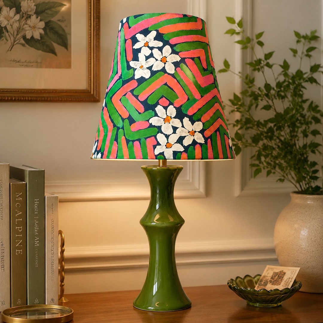 Pink and green table lamp glowing beside framed wall art