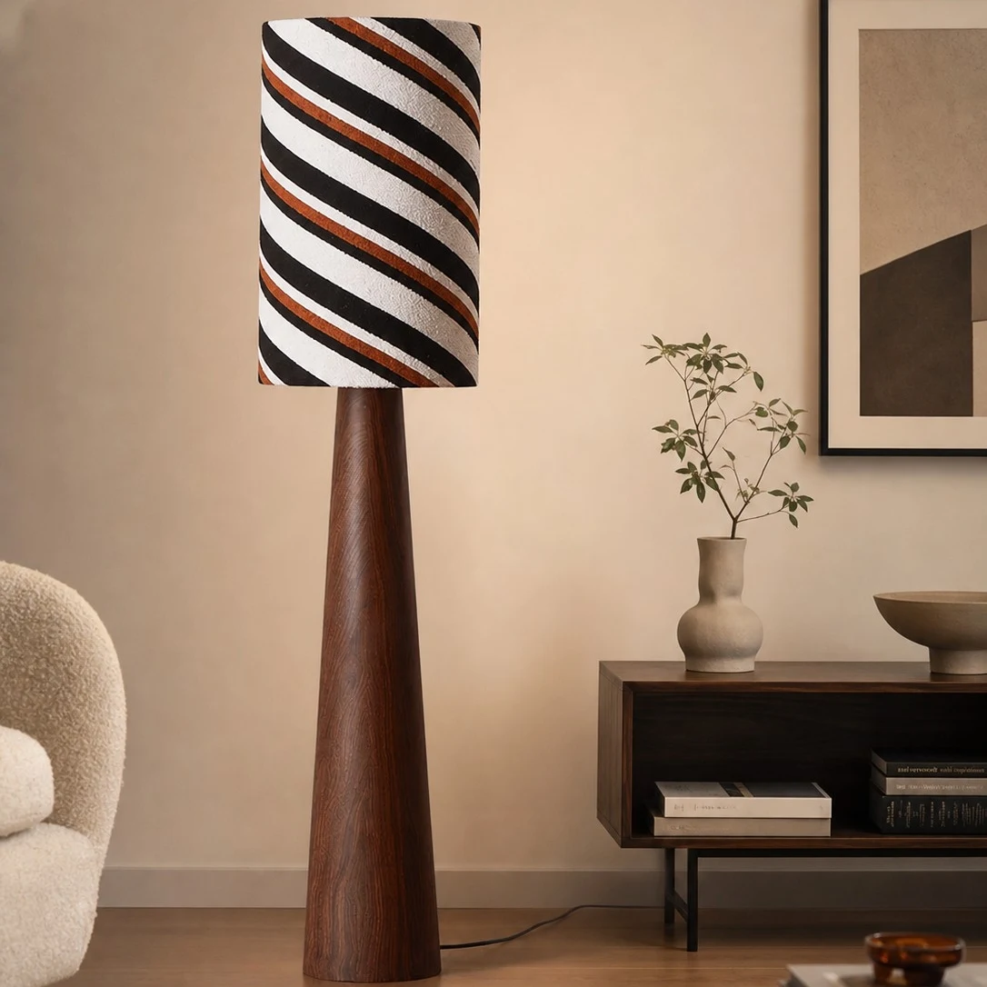 Tall striped shade floor lamp beside a console table