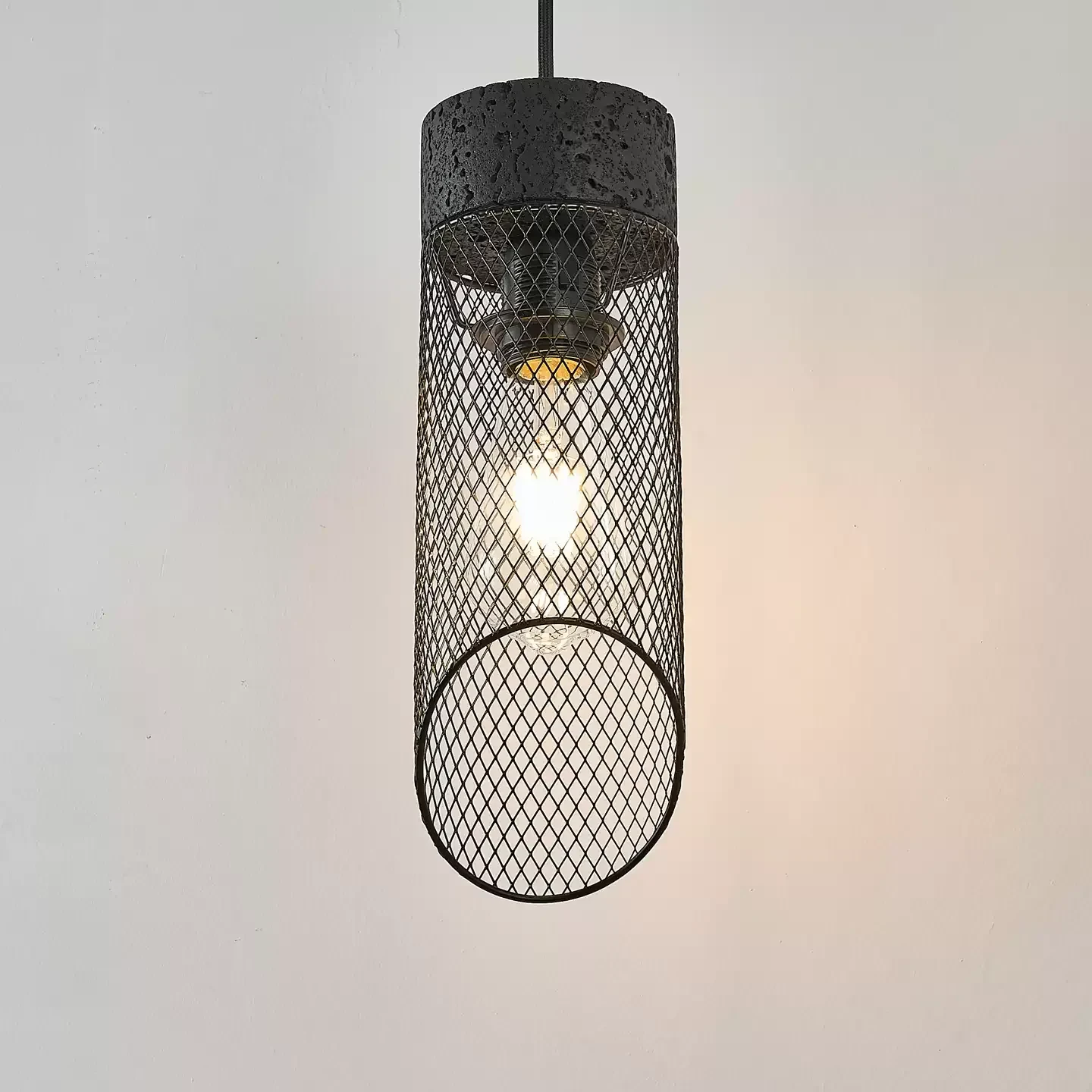 Black mesh pendant shade lit with a visible bulb inside