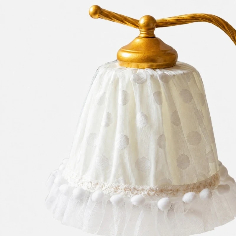 Close view of the white dotted lace shade and gold shade cap