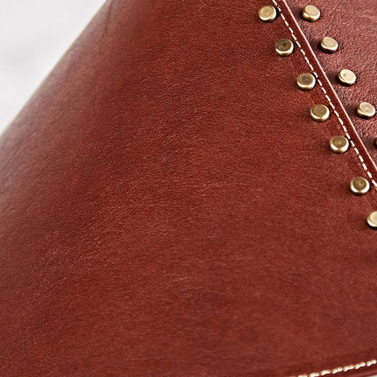 Close detail of reddish-brown leather shade with gold rivets