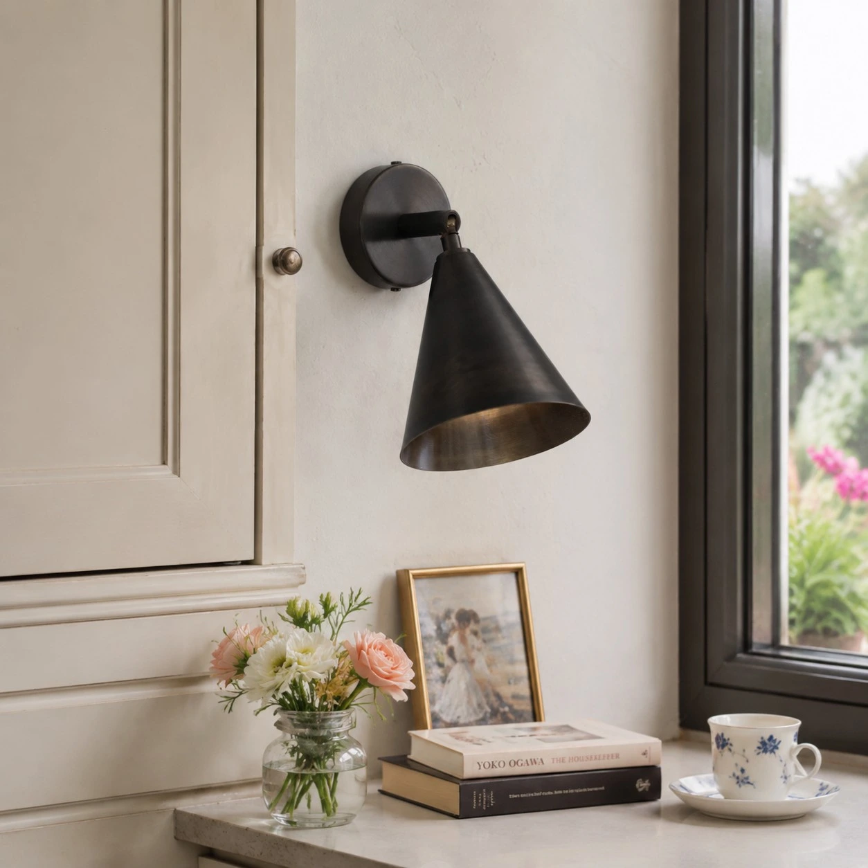 Matte black brass wall light beside a window and console