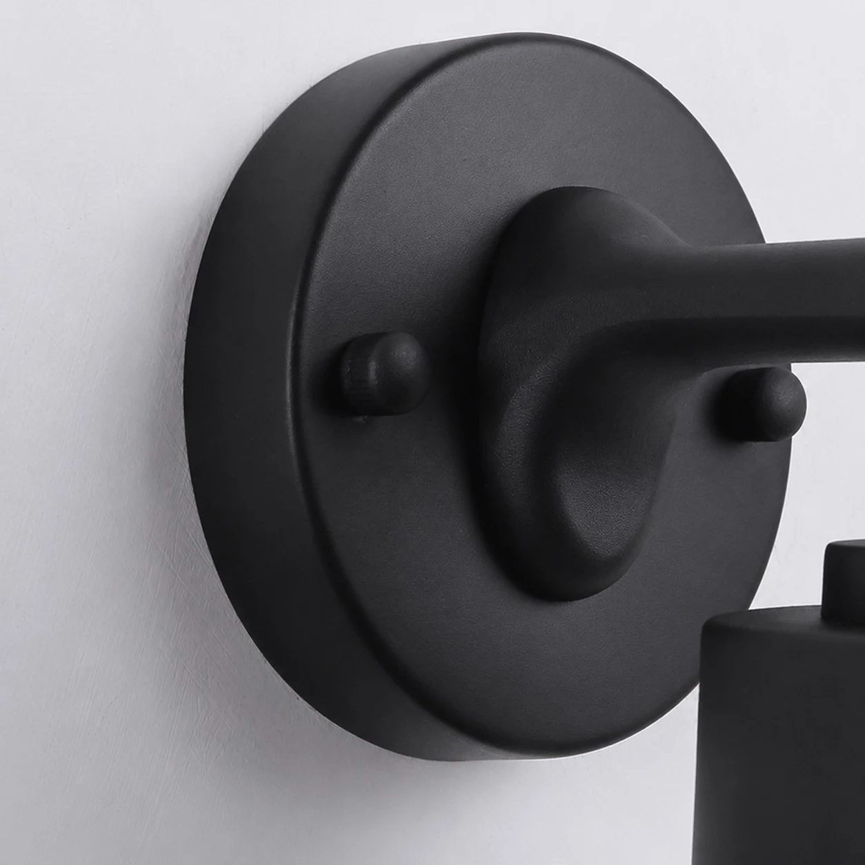 Close view of the black round wall plate and metal arm