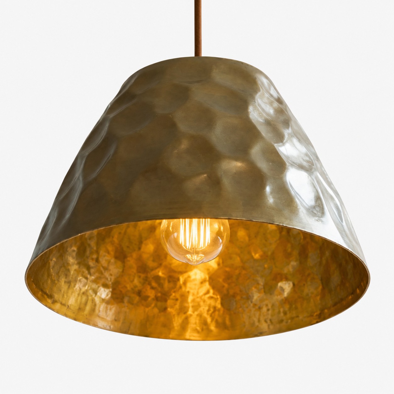 Close-up of the warm golden interior and bulb under the brass shade