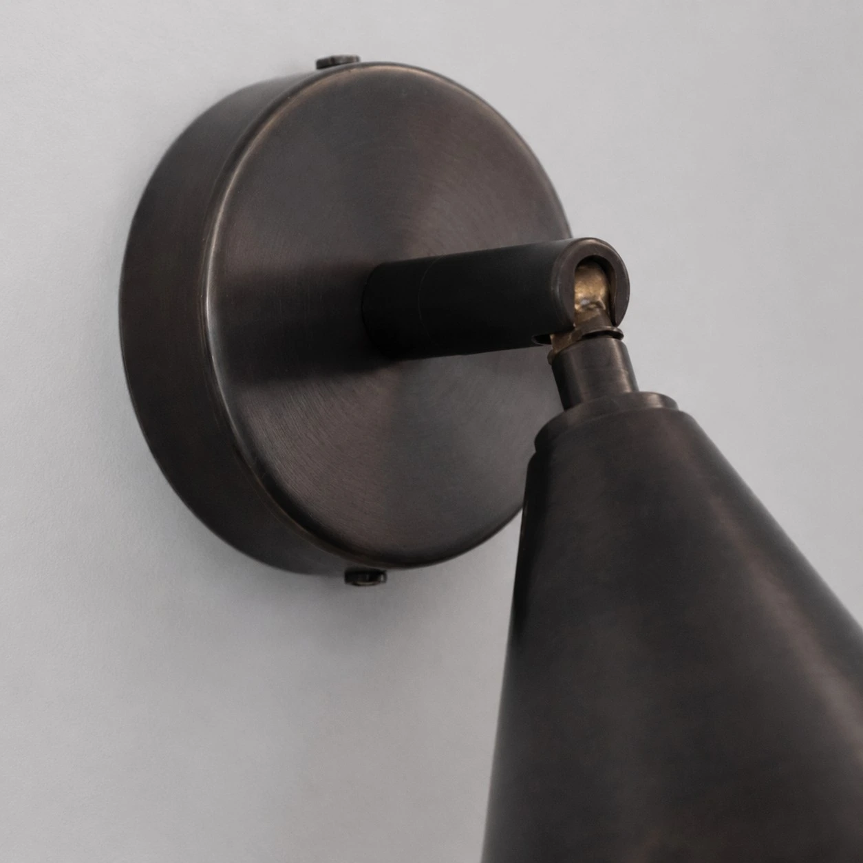 Round wall plate and adjustable arm detail on matte black wall light