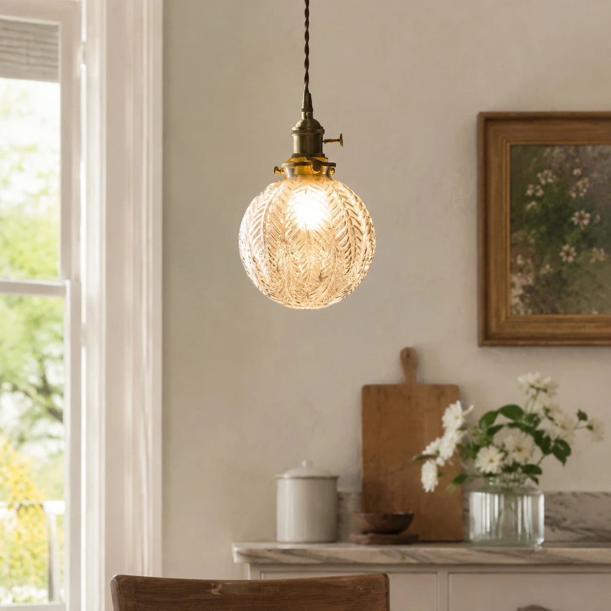 brass crackle glass pendant light glowing beside a bright window