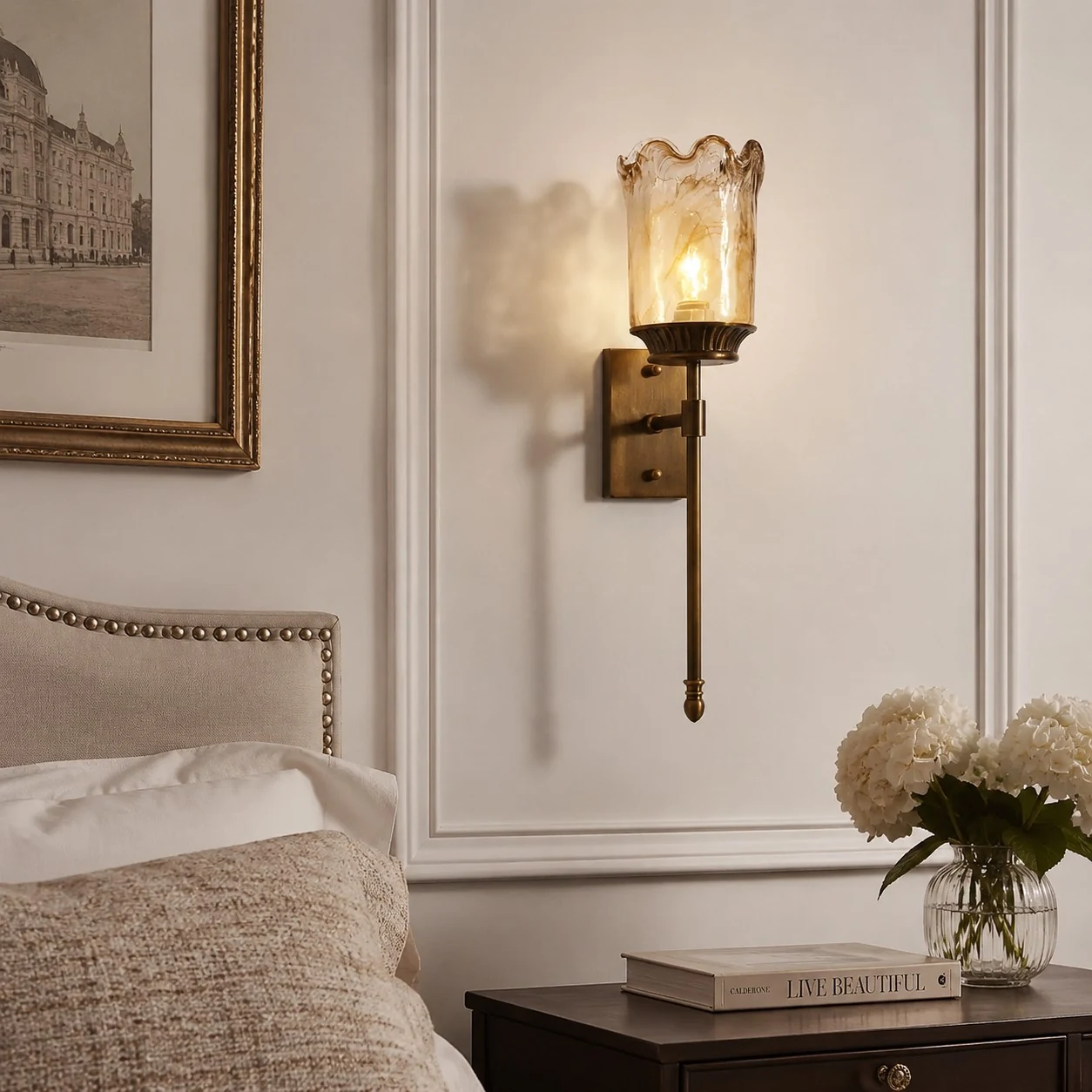 Brass amber glass wall sconce styled beside a bed