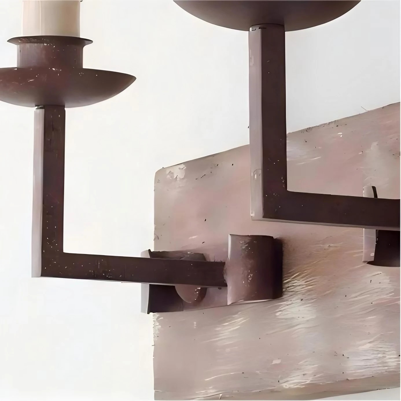 Close view of the rustic dark metal candle arm and distressed wood backplate